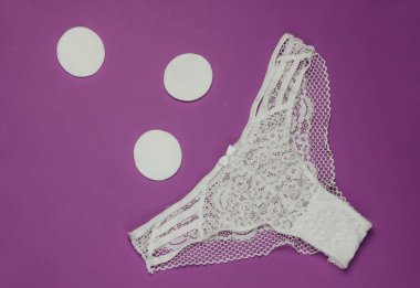 Kadın külotu ve mor arka planda ped. Kadın hijyeni konsepti. Kritik günler, adet günleri. Üst Manzara. Düz yatıyordu