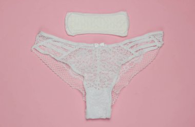 Kadın külotu ve pembe pastel arka planda ped. Kadın hijyeni konsepti. Kritik günler, adet günleri. Üst Manzara. Düz yatıyordu