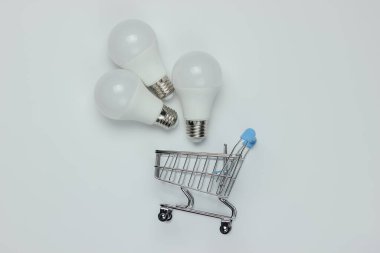 Beyaz arka planda üç LED ampul ve alışveriş arabası. Üst görünüm