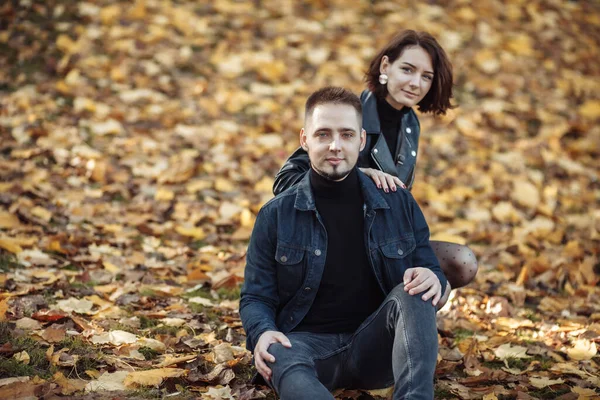 Young hugging couple of lovers on a blurry background of fallen autumn leaves in the park. Romantic, love concept