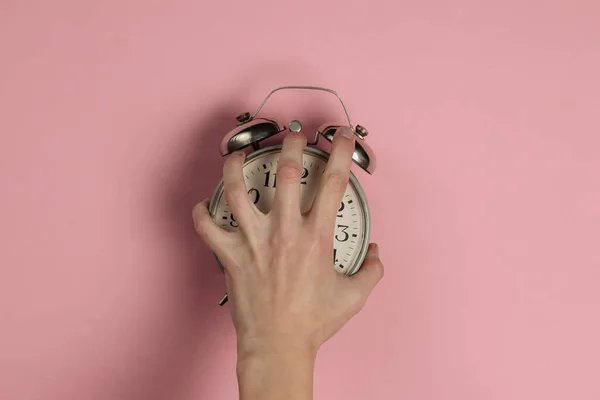 创意扁平奠定了早晨时间情绪的概念 愤怒的女性手拿着粉色粉刷背景的复古闹钟 顶部视图 工作室拍摄 — 图库照片