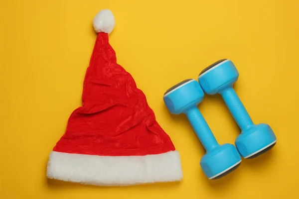 Santa Kapelusz Hantlami Żółtym Tle Koncepcja Fitness Święta Bożego Narodzenia — Zdjęcie stockowe
