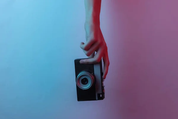 女性的手拿着一个复古相机 富有创意的流行艺术粉红蓝色霓虹灯色 趋势梯度照明 — 图库照片
