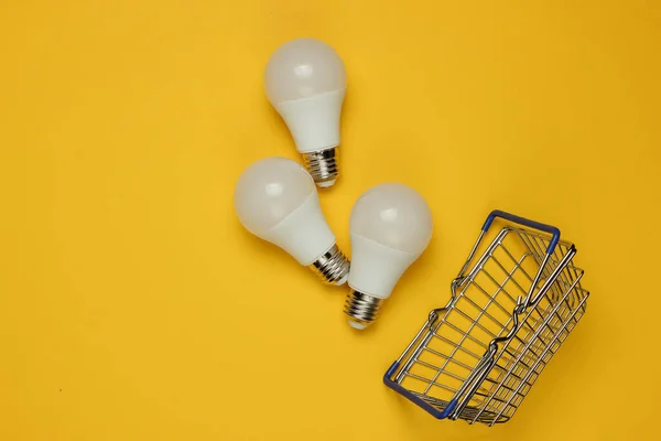 Three Led Light Bulbs Shopping Basket Yellow Background Top View — Stock Photo, Image