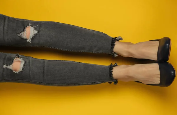 ファッショナブルなコンセプトショット 白い背景に裂けた膝とハイヒールの靴を履いたグレーのジーンズを着た女性の足 最上階だ ミニマリズム — ストック写真