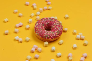 Minimalist yiyecekler hala hayattadır. Sarı zemin üzerinde lokum olan jöleli donut..