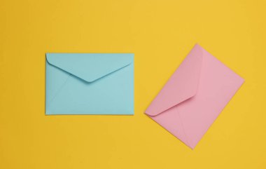 Sarı arka planda iki zarf pembe ve mavi pastel renkli. Sevgililer günü, düğün ya da doğum günü için düz yatış modeli