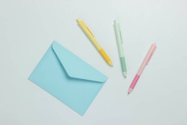 Beyaz arka planda zarf ve renkli kalemler. Üst görünüm