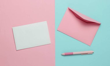 Zarfta mavi pembe pastel arka planda bir mektup ve kalem var. Sevgililer günü, düğün ya da doğum günü. Üst görünüm