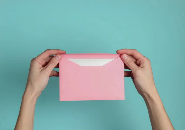 女性の手は青いパステルの背景に手紙で封筒を保持しています 最上階だ バレンタインデー結婚式招待状愛の手紙 — ストック写真