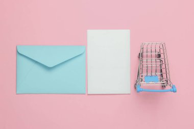 Pembe bir zarf ve pembe pastel arka planda alışveriş arabası. Sevgililer günü, düğün ya da doğum günü için bir model. Üst görünüm