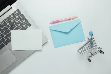 Laptop ve zarf, beyaz arka planda alışveriş arabası. Sevgililer Günü. Üst görünüm