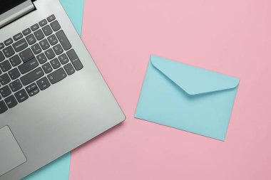 Laptop ve zarf pembe mavi pastel arka planda. Sevgililer Günü. Üst görünüm