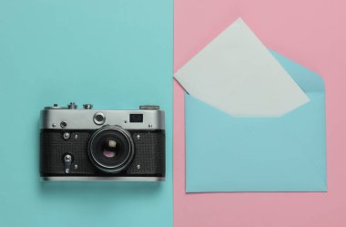 Zarfta bir harf, pembe mavi pastel arka planda retro kamera. Üst Manzara. Seyahat kavramı