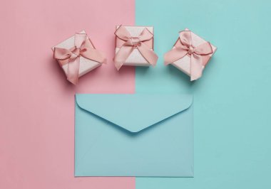 Zarf, pembe mavi pastel arka planda hediye kutuları. Noel, sevgililer günü, düğün ya da doğum günü. Üst görünüm
