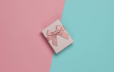 Mavi-pembe pastel arka planlı bir hediye kutusu. Noel, doğum günü ya da düğün için kompozisyon. Üst görünüm