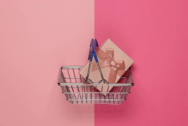 Alışveriş sepeti ve pembe renkli fiyonklu hediye kutusu. Noel, doğum günü ya da düğün için kompozisyon. Üst görünüm