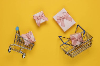 Alışveriş sepeti ve tramvay, sarı arka planda fiyonklu hediye kutusu. Noel, doğum günü ya da düğün için kompozisyon. Üst görünüm