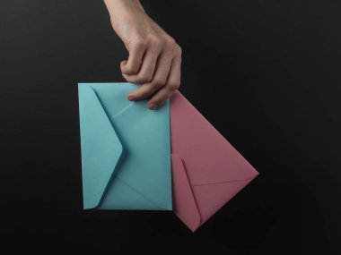 Kadın eli, siyah bir arkaplanda zarfları tutuyor.