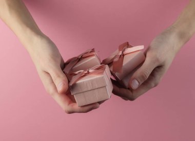 Kadınların elinde pembe pastel arka planda hediye kutuları var. Doğum günü kavramı, Noel, Sevgililer Günü