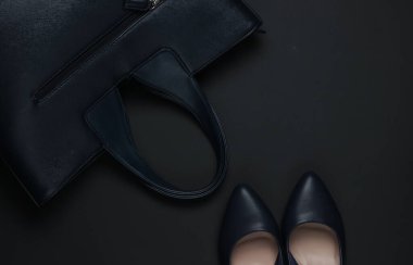 Siyah arka planda kadın aksesuarları. Yüksek topuklu ayakkabılar, deri çanta. Üst görünüm