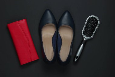 Siyah arka planda kadın aksesuarları. Yüksek topuklu ayakkabılar, deri çanta, tarak. Üst görünüm