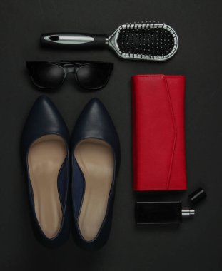 Siyah arka planda kadın aksesuarları. Yüksek topuklu ayakkabı, tarak, güneş gözlüğü, parfüm şişesi, çanta. Üst görünüm