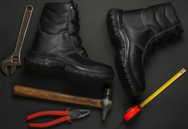Farklı endüstriyel araç ve gereçlerle donatılmış düz kompozisyon, siyah arka planda güvenlik ekipmanları. Üst görünüm