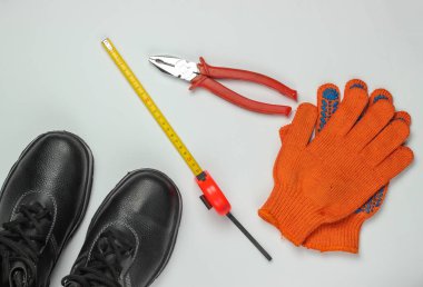 Farklı endüstriyel aletler ve aletlerle bembeyaz arka planda güvenlik ekipmanları olan düz bir kompozisyon. Üst görünüm