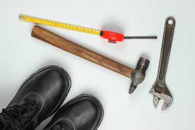 Farklı endüstriyel aletler ve aletlerle bembeyaz arka planda güvenlik ekipmanları olan düz bir kompozisyon. Üst görünüm