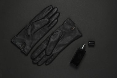 Siyah arka planda kadın moda aksesuarları. Deri eldivenler, parfüm şişesi. Üst görünüm
