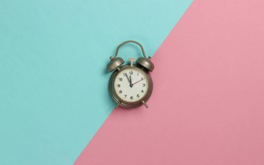 Pembe pastel arka planda geçmişe dönük alarm saati. 11: 55 'te. Yeni yıl. Üst görünüm