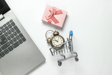 Laptop, retro çalar saat, alışveriş arabası, beyaz arka planda fiyonklu hediye kutuları. 11: 55 'te. Yeni yıl, Noel konsepti. Tatiller online alışveriş. Üst görünüm