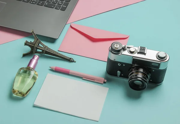 Envelope with letter, retro camera, laptop and beauty accessories on pink blue pastel background. Top view. Travel concept.