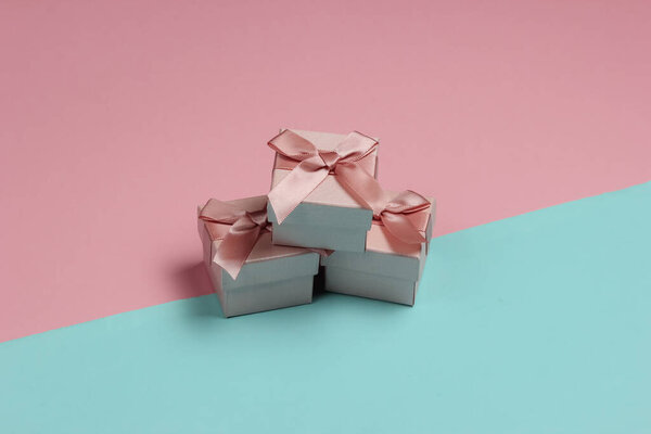 Gift boxes with bow on blue-pink pastel background. Composition for christmas, birthday or wedding.