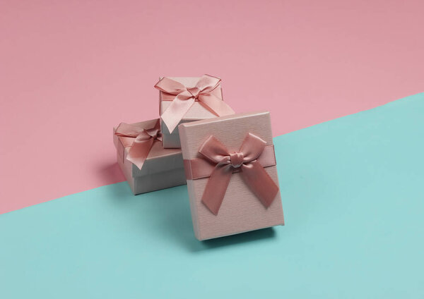 Gift boxes with bow on blue-pink pastel background. Composition for christmas, birthday or wedding.