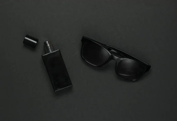 Women's accessories on a black background. Sunglasses, perfume bottle. Top view