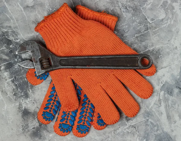 Work gloves and wrench on a gray concrete background. Top view