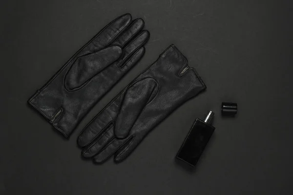 Women\'s fashion accessories on a black background. Leather gloves, perfume bottle. Top view
