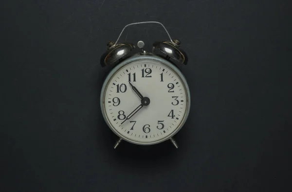 Retro alarm clock on a black background. Top view