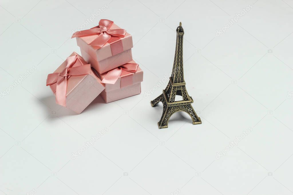 gift boxes with bows and a statuette of the Eiffel Tower on a white background. Shopping in Paris, souvenirs