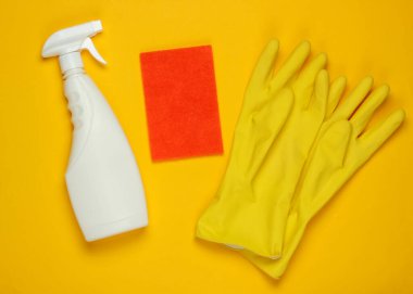 Temizlik için beyaz sprey, eldivenler, sarı arka planda sünger. Üst Manzara. Minimalizm