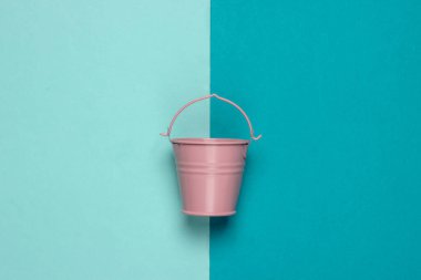 Mavi pastel arka planda pembe boş bir kova. Minimalizm. Moda rengi konsepti. Üst görünüm