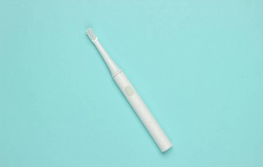 Mavi pastel arka planda modern elektrikli diş fırçası. Diş bakımı konsepti. Üst Manzara. Minimalizm