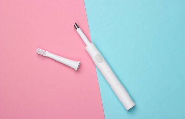 Pembe arka planda başlığı olan modern elektrikli diş fırçası. Üst görünüm