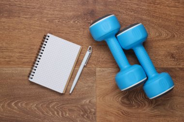 Gelecekteki antrenmanlarını planla. Bir eğitim programı hazırlıyorum. Kalem ve halterli defter yere. Spor, spor konsepti.