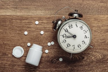 Uykusuzluk konsepti. Alarm saati ve yerde bir şişe hap. Üst görünüm