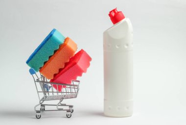 Temizlik konsepti. Deterjan şişeli alışveriş arabası, beyaz arka planda süngerler.
