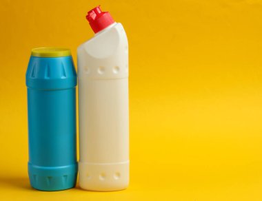 Temizlik konsepti. Sarı arka planda deterjan şişeleri. Boşluğu kopyala