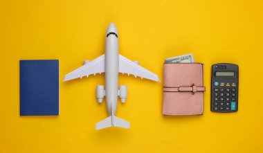 Dinlenmenin, göç etmenin, uçak yolculuğunun maliyetinin hesaplanması. Seyahat geçmişi. Gezgin, turist aksesuarları, oyuncak uçak, sarı arka planda hesap makinesi. Üst görünüm.